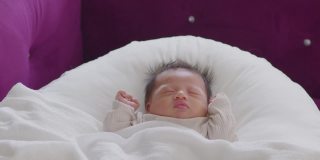 特写快乐的新生儿躺在白色的毯子上睡觉，舒适和安全。可爱的亚洲新生儿在床上睡觉和打盹。新生儿摄影理念