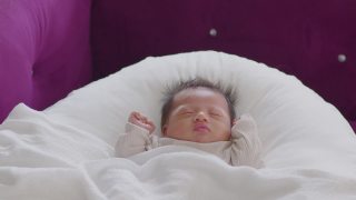 特写快乐的新生儿躺在白色的毯子上睡觉，舒适和安全。可爱的亚洲新生儿在床上睡觉和打盹。新生儿摄影理念视频素材模板下载