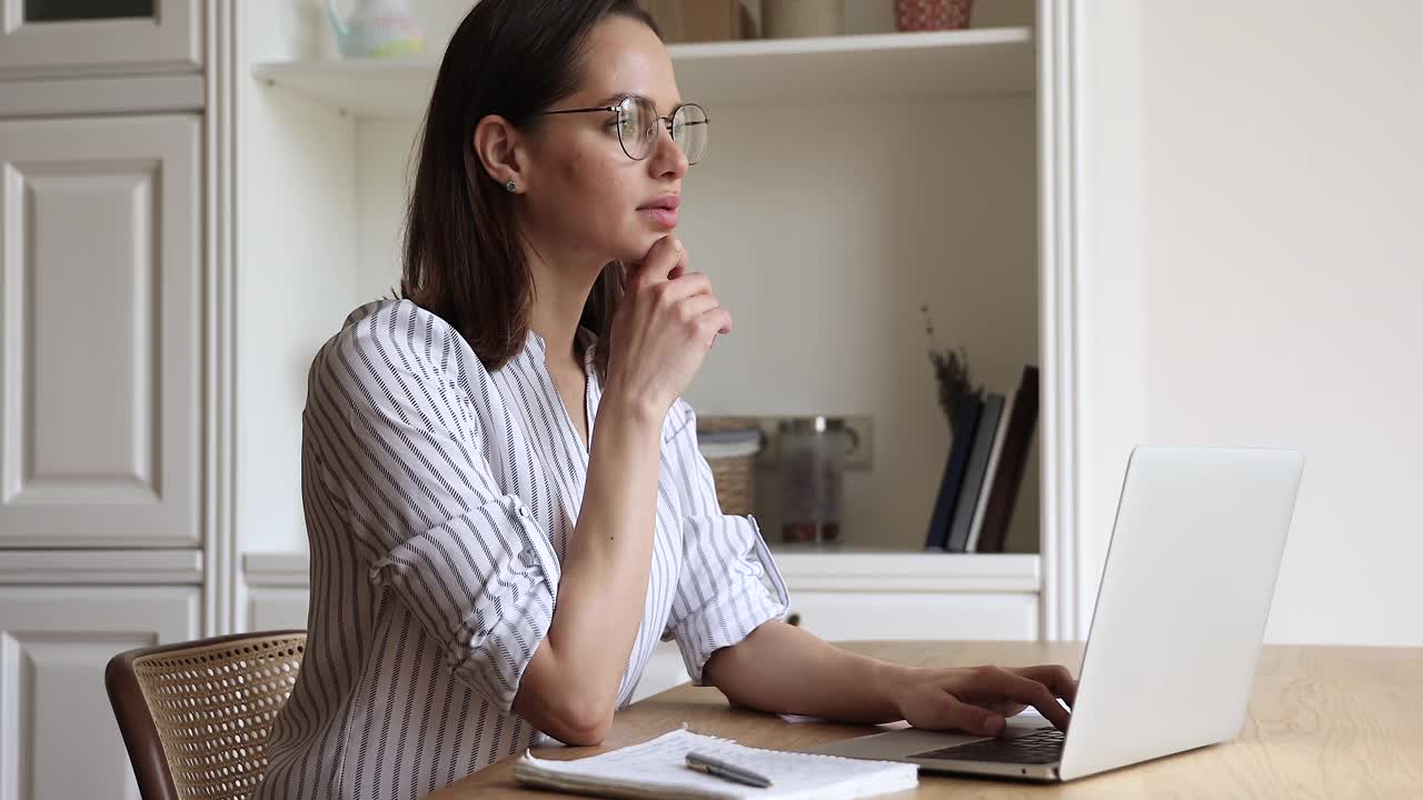 专注的女性在笔记本电脑上浏览网站信息做笔记