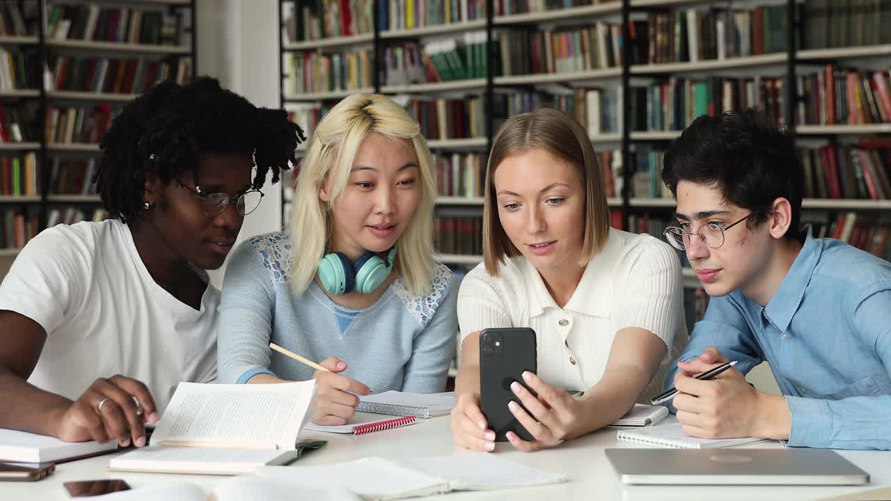 不同的学生小组坐在图书馆玩手机