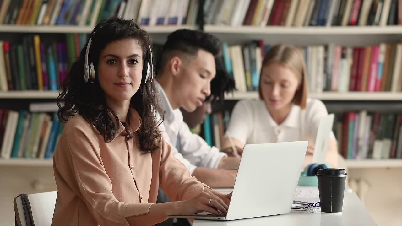 女孩戴着耳机学习，坐在图书馆里用笔记本电脑