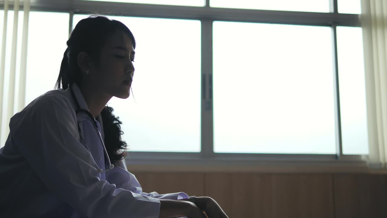 一个沮丧的年轻女子坐在椅子上，压力和焦虑。她独自坐在医院里，为自己的健康担心。