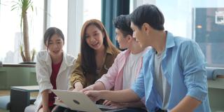 一群亚洲高中生在办公室会议室开会，用笔记本电脑检查统计数据，分析市场，并考虑营销活动。