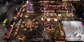 圣诞市场，鸟瞰。圣诞旋转木马，溜冰场，巨大的装饰圣诞树和摩天轮。现代城市灯火通明的圣诞集市。