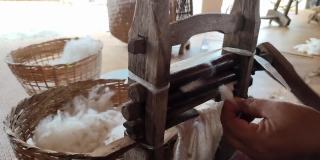 在泰国，成熟的亚洲妇女用老式的传统机器将棉籽从棉花中分离出来