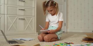 专注漂亮小学女生坐在家里的地板上写作业，慢动作。