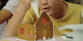 亚洲男孩和妹妹在晚上在家做姜饼屋，庆祝圣诞节的生活理念。