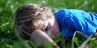 孩子躺在外面的草地上做着白日梦玩耍