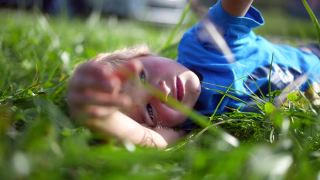 孩子躺在外面的草地上做着白日梦玩耍视频素材模板下载