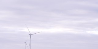 在海上或野外的大农场全速旋转叶片。旋转的风车在灰色的天空背景。由风力涡轮机产生的清洁可再生能源。另一种生活方式