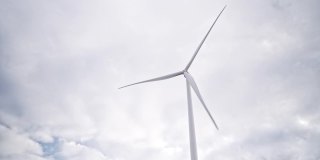 在海上或野外的大农场全速旋转叶片。旋转风车在灰色天空的背景。由风力涡轮机产生的清洁可再生能源。另一种生活方式