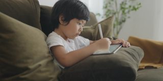 亚洲男孩数字艺术家绘画在一个图形平板电脑。