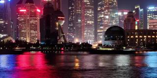 夜晚从外滩俯瞰上海的天际线，摩天大楼和地标建筑与黄浦江上的船只一起航行，延时4k镜头b滚动镜头缩放效果。