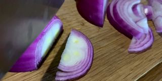 用菜刀在砧板上切红洋葱。
