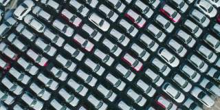 从空中俯瞰的新汽车停在停车场。汽车经销商的停车场满是新车。新车排队等待进出口业务。