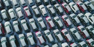 从空中俯瞰的新汽车停在停车场。汽车经销商的停车场满是新车。新车排队等待进出口业务。