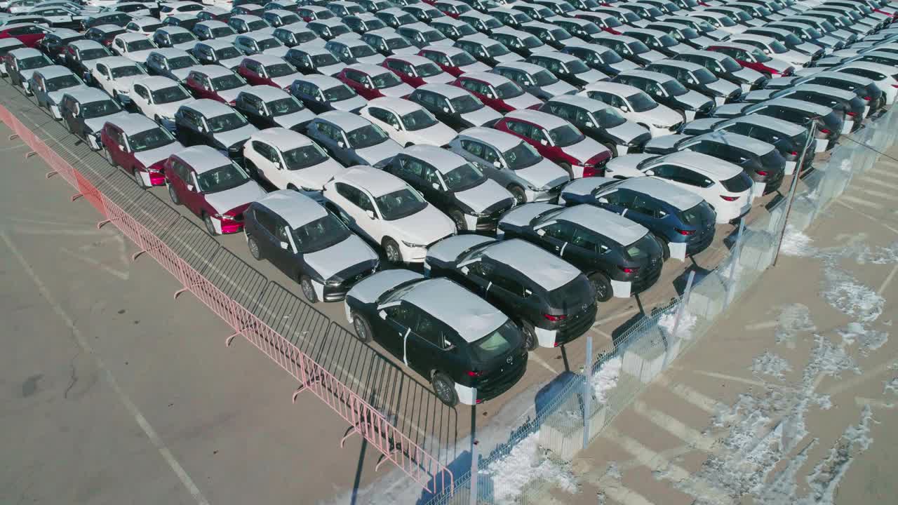 鸟瞰图的新车停在停车场。汽车经销商的停车场满是新车。新车排队等待进出口业务。