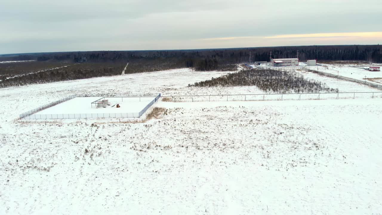 一架无人机在该国北部工业区的积雪覆盖地区上空飞行。一辆小型拖拉机装载机用设备清理建筑物附近的积雪