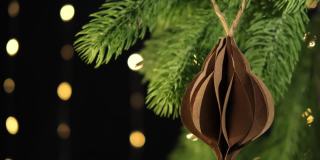Diy纸装饰物特写挂在云杉树枝上，雪花飘落。圣诞节可持续装饰。缓慢的运动。有选择性的重点。