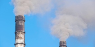 火力发电厂高管道的特写，黑烟向上移动，污染大气。用化石燃料生产电能的概念