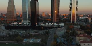 在日落时分，向前飞向Cuatro Torres商业区的现代摩天大楼。一排高层办公大楼