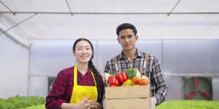 肖像年轻的亚洲夫妇拿着箱子与蔬菜。