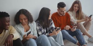现代的年轻人沟通。一群兴高采烈的年轻朋友在一起聊天，在智能手机上分享新闻