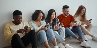 社交媒体上瘾。一群多种族的年轻人在智能手机上上网，忽略了真正的交流