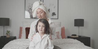 亚洲母亲假装玩身体按摩和她的女儿在床上，家庭生活方式健康的概念