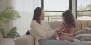 亚洲母亲和混合学前班女儿在家里玩挠痒痒游戏，家庭健康理念