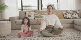 亚洲母亲和混血亚洲女儿在家练习瑜伽在线流课程，家庭在线学习一起，健康的生活方式健康的理念