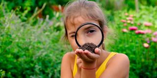 这孩子用放大镜研究土壤。有选择性的重点。孩子。