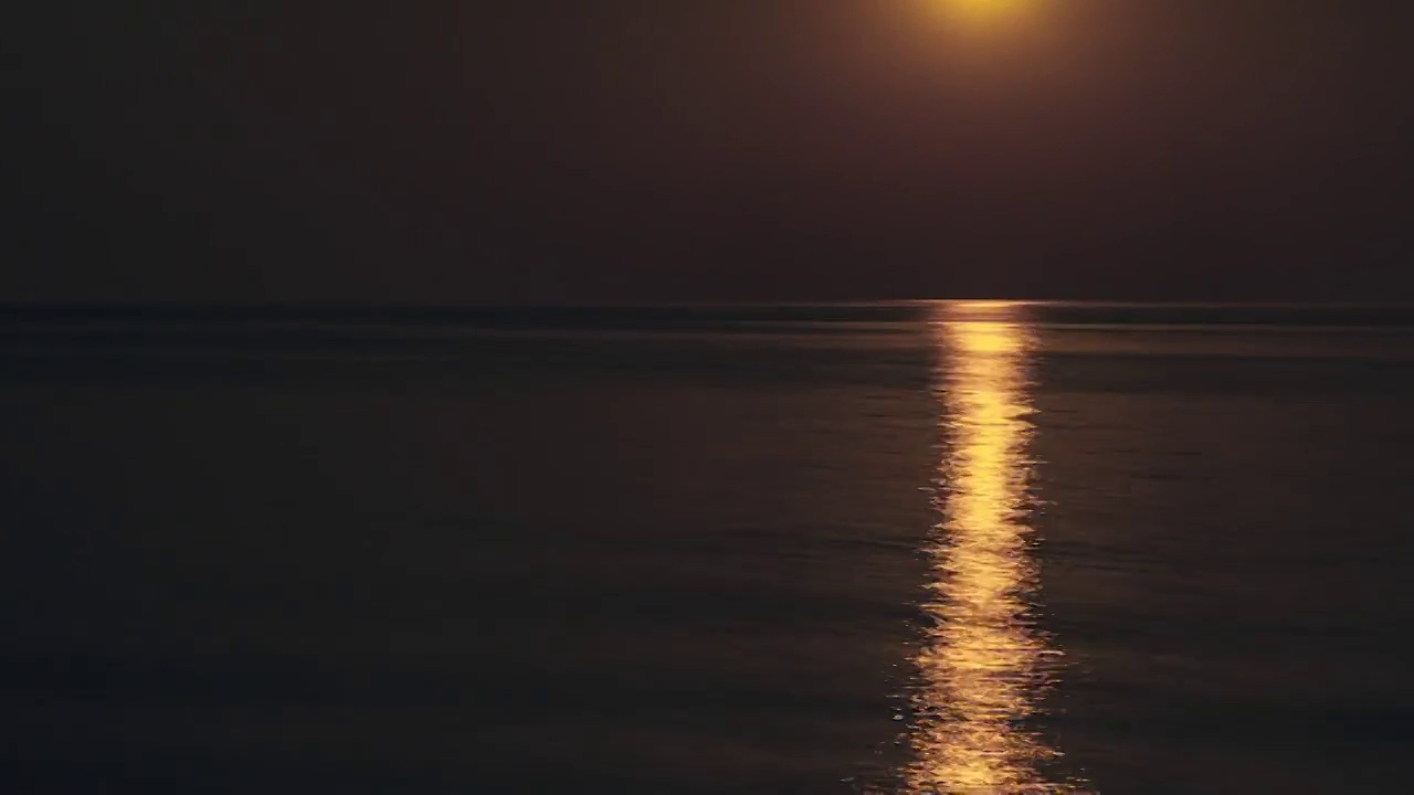 水面上美丽的延时月亮之路。在一个黑暗的夜晚，平静的海面上，满月明亮地照耀着天空