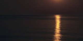 水面上美丽的延时月亮之路。在一个黑暗的夜晚，平静的海面上，满月明亮地照耀着天空