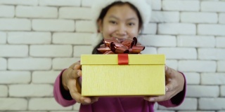 亚洲快乐女孩送礼盒在砖墙背景上。