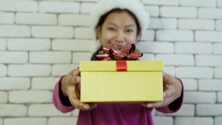 亚洲快乐女孩送礼盒在砖墙背景上。视频素材模板下载