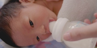近距离观察亚洲母亲用奶瓶喂婴儿。
