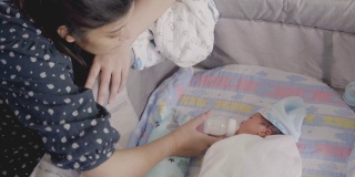 亚洲母亲喂婴儿的奶瓶男孩。
