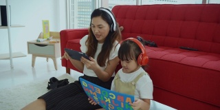 家人、妈妈和她的孩子用数码平板电脑听音乐和看视频。