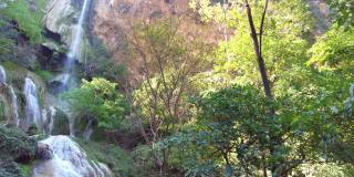 四面湾瀑布位于泰国曼谷北碧府国家公园的山脉中，可爱的蓝绿色奶油色的水，郁郁葱葱的树木，光滑的岩层