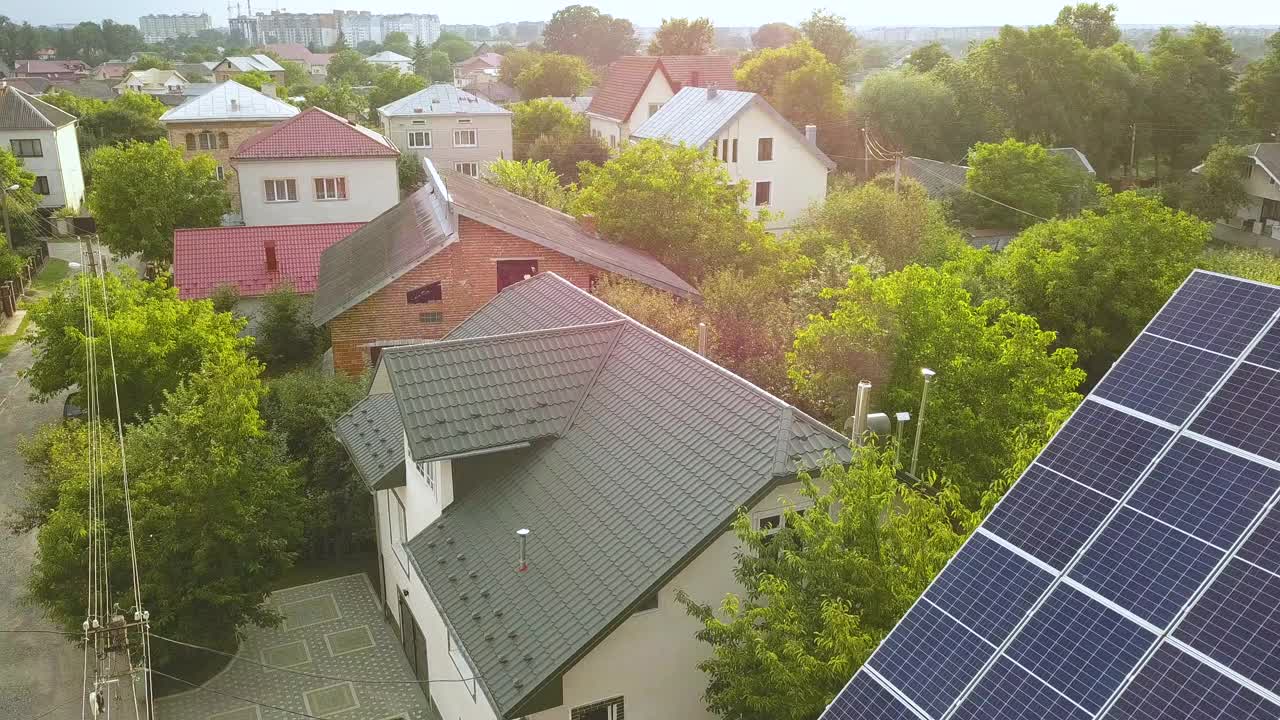 空中俯瞰的新现代住宅小屋与蓝色闪亮的太阳能光伏板系统屋顶。可再生生态绿色能源生产理念。