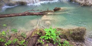 四面湾瀑布位于泰国曼谷北碧府国家公园的山脉中，可爱的蓝绿色奶油色的水，郁郁葱葱的树木，光滑的岩层
