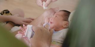 靠近亚洲妈妈的手清洁婴儿眼睛，婴儿哭。
