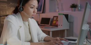 呼叫中心工作人员使用电脑打字，戴着耳机在办公室里上夜班