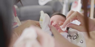 靠近亚洲妈妈的手清洁婴儿眼睛，婴儿哭。