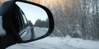 冬季森林道路的侧视镜反射。风景与空旷的高速公路穿过雪原森林。汽车在路上超速行驶。汽车在运动。旅游，旅行，旅行概念。冰雪覆盖的树木。