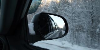 冬季森林道路的侧视镜反射。风景与空旷的高速公路穿过雪原森林。汽车在路上超速行驶。汽车在运动。旅游，旅行，旅行概念。冰雪覆盖的树木。