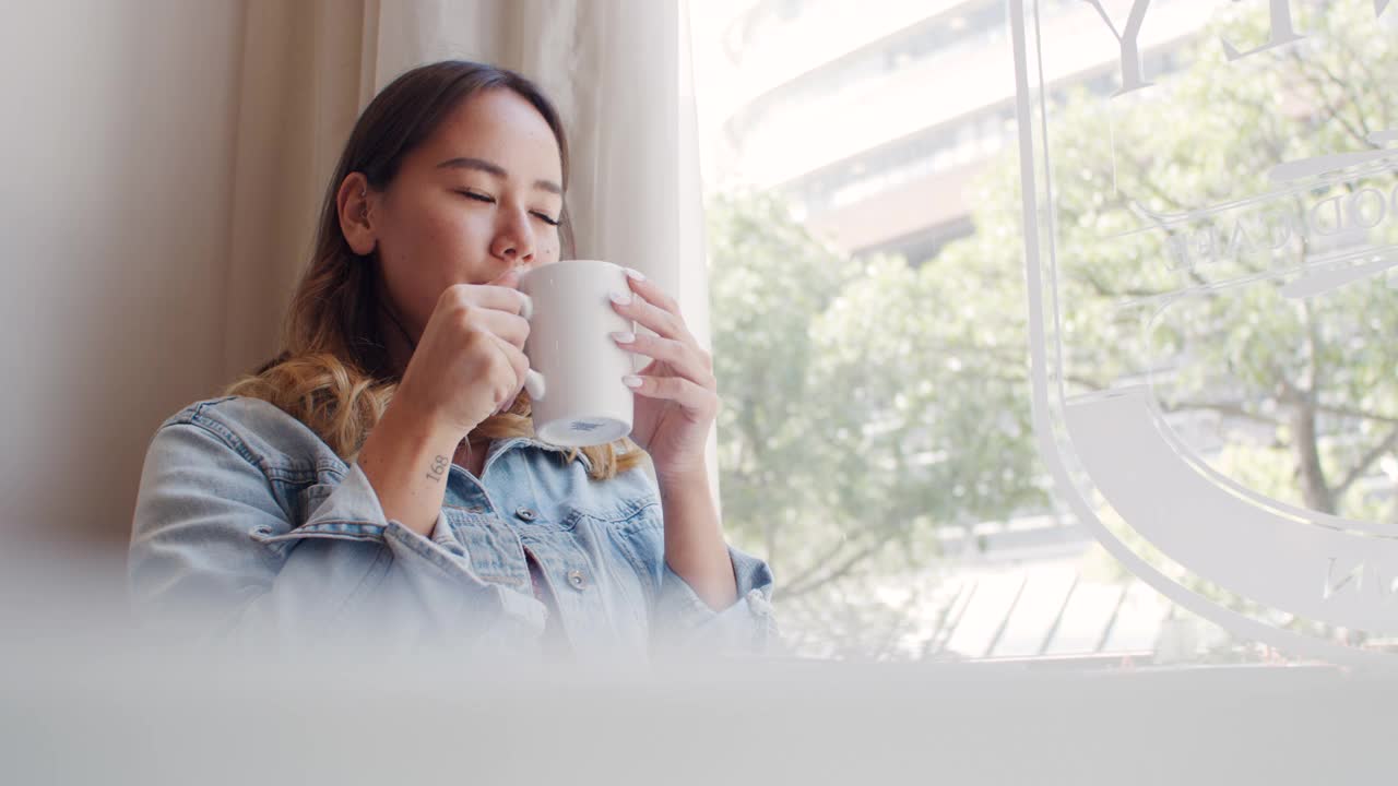 一个迷人的年轻女子在她最喜欢的咖啡馆享受咖啡的4k视频片段