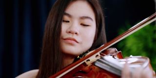 在节日聚会上演奏小提琴的年轻亚洲女人