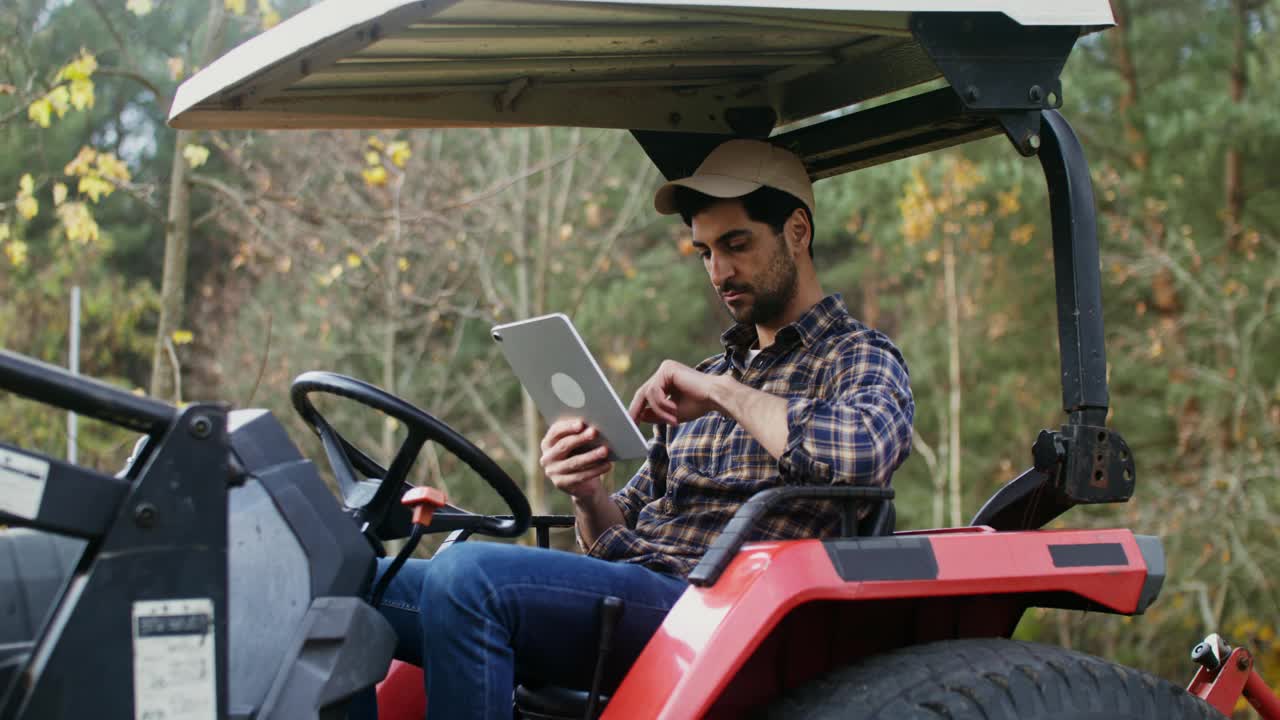 一名年轻人坐在一台立式农机里使用平板电脑